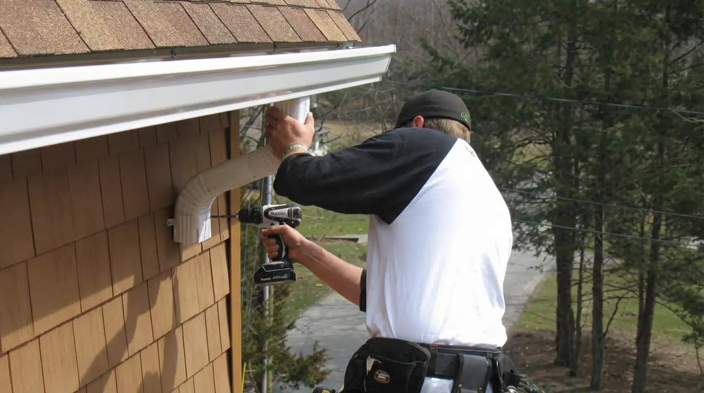 Professional contractor installing tan vinyl siding panels on a residential home exterior in Jersey City, NJ